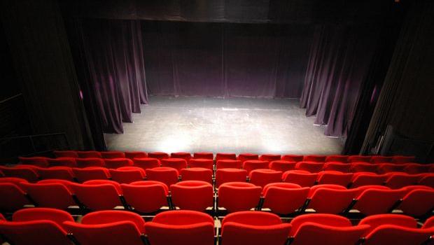 Scène de théâtre sous projecteurs avec rangées de sièges rouges