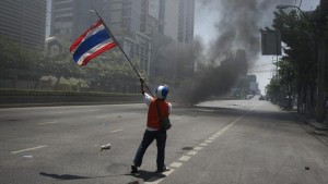 guerre civile à bangkok en thaïlande, personne qui agite le drapeau thailandais devant la fumée