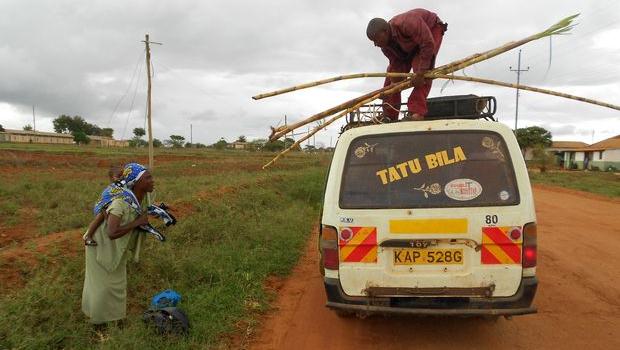 Un kenyan manipule des tiges de canne à sucre sur le toit d'un matatu