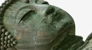 Massive tête de statue de Bouddha grise allongée et fissurée