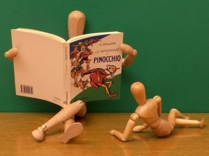 bonhommes marionnettes de bois en train de lire les aventures de Pinocchio
