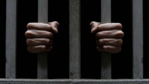 Deux mains qui tiennent les barreaux d'une prison
