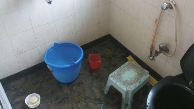 Salle de bain indienne avec le seau d'eau et le jet d'eau