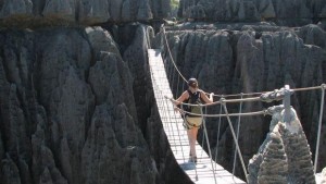 une courageuse backpackeuse aventurière franchit un pont de singe au-dessus du vide d'un ravin